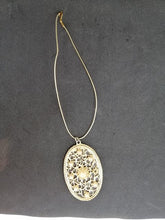 Charger l&#39;image dans la galerie, Collier en métal doré avec pendentif avec de perles et derrière un miroir

